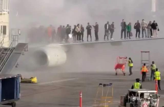 passengers stand on wing as they evacuate after plane bursts into flames at 19777