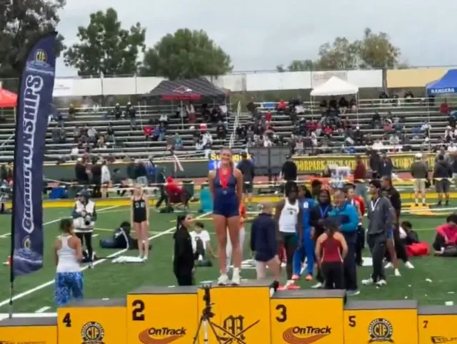 high school female track star poses on first-place podium after finishing s 24545