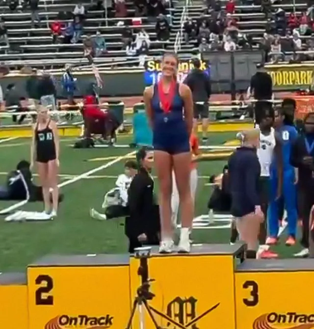 high school female track star poses on first-place podium after finishing s 24546